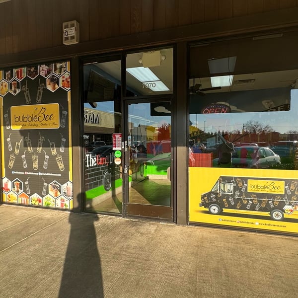 Exterior of BubbleBee bubble tea shop with large window decals featuring drinks and a food truck.