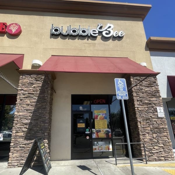 Exterior of Bubble Bee, a boba tea shop, with a red awning and stone facade.